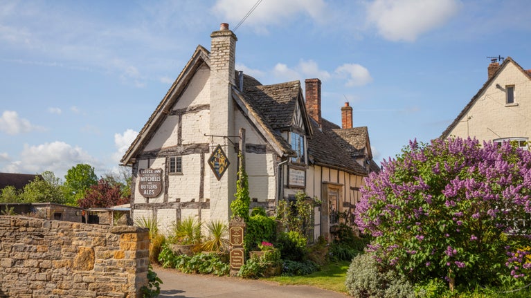 A pub in the spring sunshine with blue skies surrounding and flowers growing